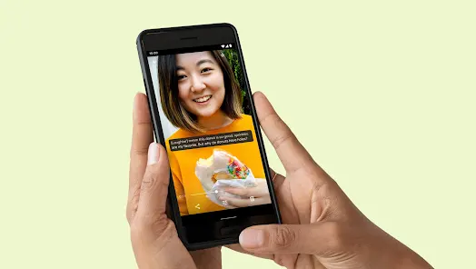 Un celular Android mostrando el video de una mujer con subtítulos. De fondo una pared amarillo claro